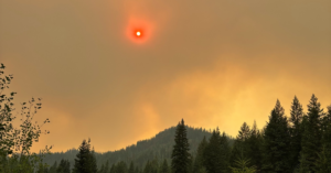 Smoky skies and red sun over forested hills outside of Colville, Washington