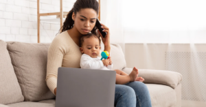 Woman on the phone with a baby in her lap looking at a laptop