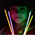 child holding glow sticks in front of his face